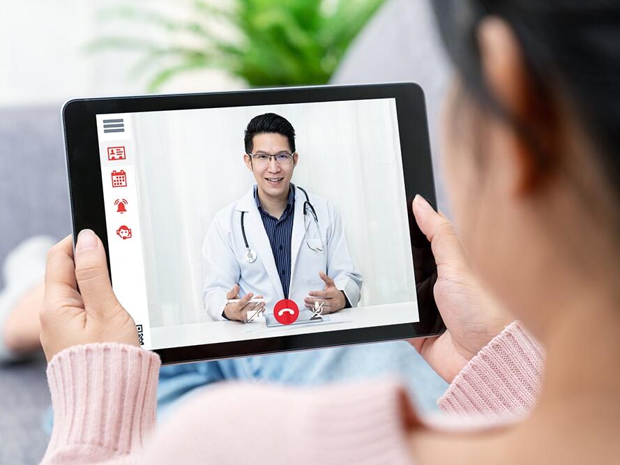 Smiling doctor on a tablet screen meeting with his patient.
